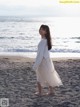 A young girl standing on a beach next to the ocean.