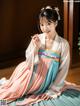 A woman in a pink and blue hanbok sitting on the floor.