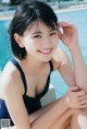 A woman in a blue bathing suit sitting by a swimming pool.