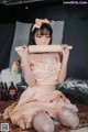 A woman in a pink dress holding a rolling pin.