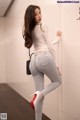 A woman leaning against a wall with her back to the camera.