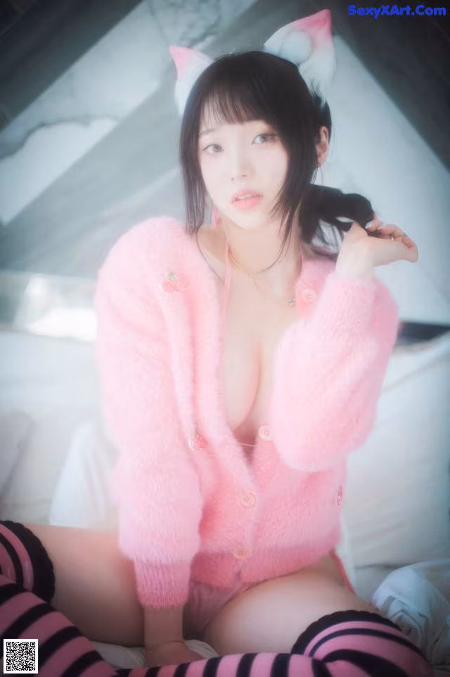A woman in a pink sweater and striped stockings sitting on a bed.
