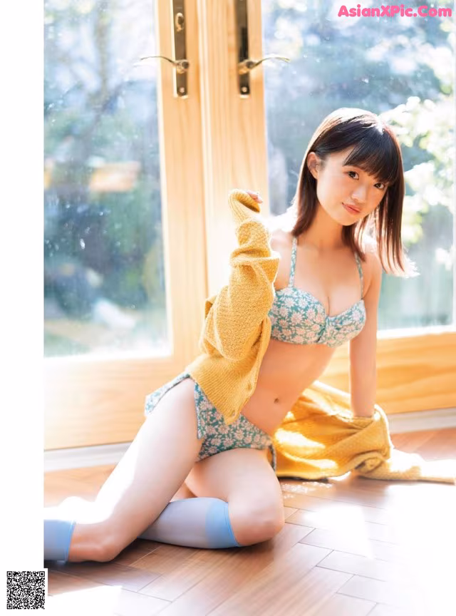 A woman in a bikini sitting on the floor.