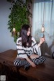 A woman sitting on a wooden table holding a light bulb.