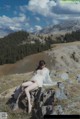 A woman sitting on top of a mountain next to a lake.