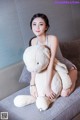 A woman sitting on a couch holding a large stuffed animal.