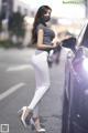 A woman wearing a face mask standing next to a car.