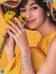 A woman in a yellow dress holding a bunch of yellow flowers.